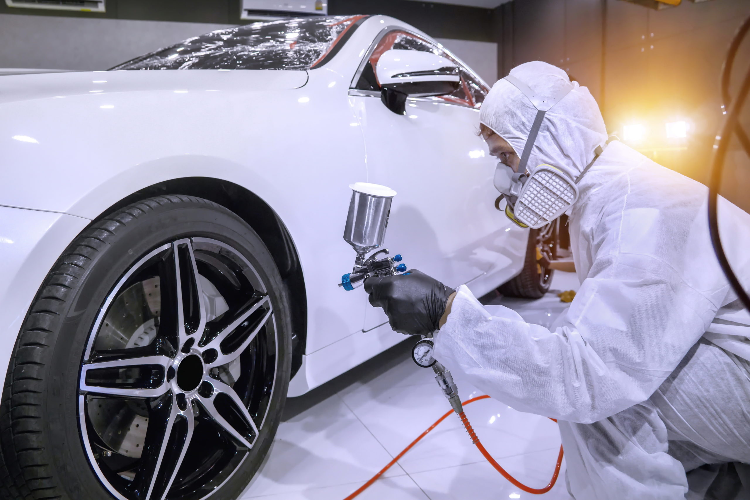 An auto paint tech painting a sporty car white. BarCan barite paint components are an environmentally safer alternative to other white paint constituents like titanium.