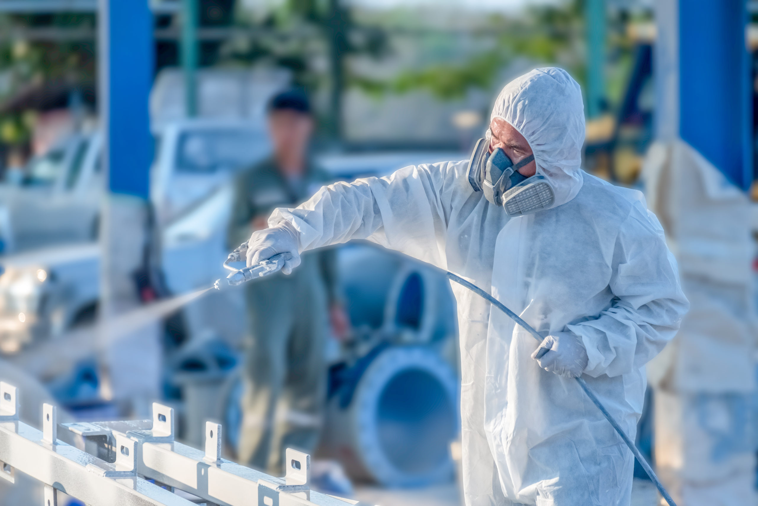 A commercial painter using compressed air to spray white paint in an industrial setting. BarCan barite is used to replace unsafe paint additives in high-quality paints used in homes and offices around the world.