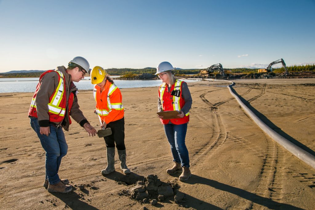 On the BarCan site, R Brace, F Humber and T Pinsent examine some Dry Feed nearby the Feed line to the Kwatani